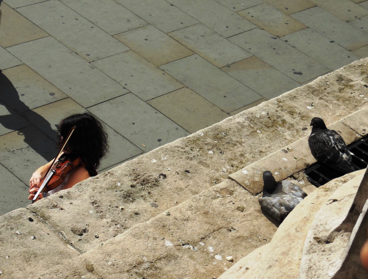 In front of the National Gallery in London, looking down from the stairs on a street artist.